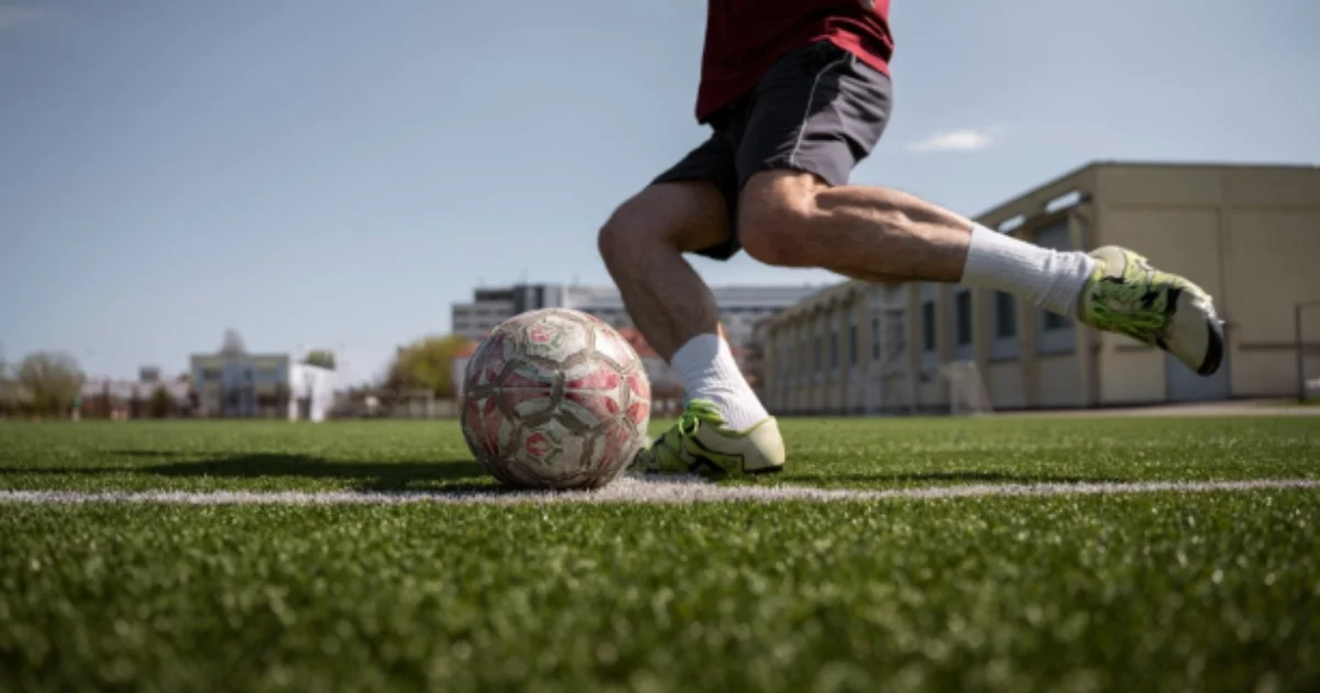 A close-up of a soccer player preparing to kick a ball on an artificial turf field.